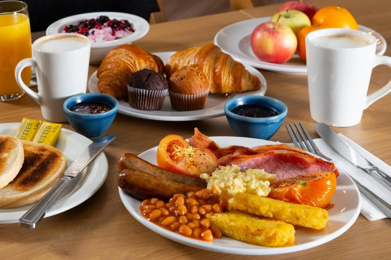 a table with plates of breakfast food on it at Holiday Inn Express Cambridge by IHG in Cambridge