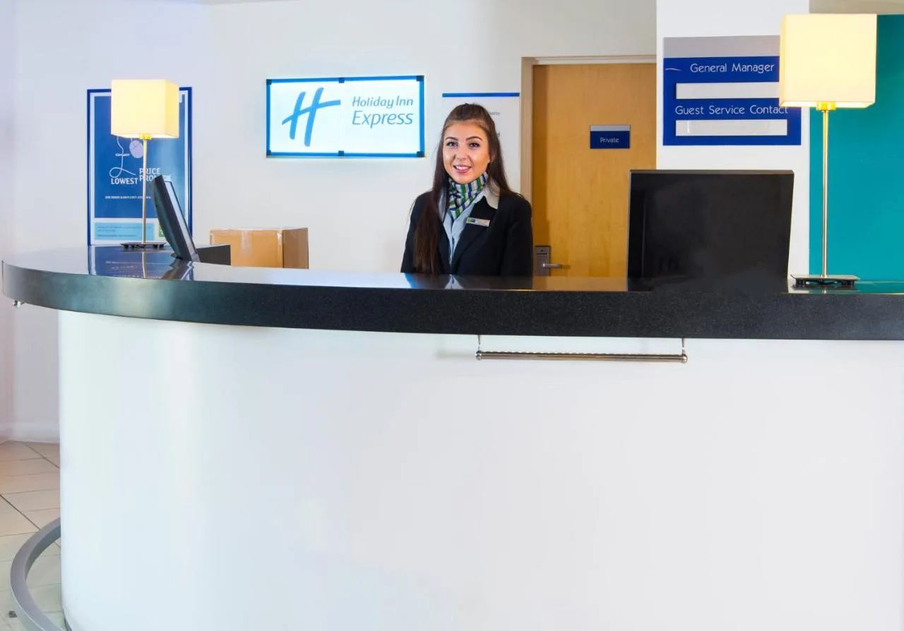 a woman is sitting at a reception desk at Holiday Inn Express Cambridge by IHG in Cambridge
